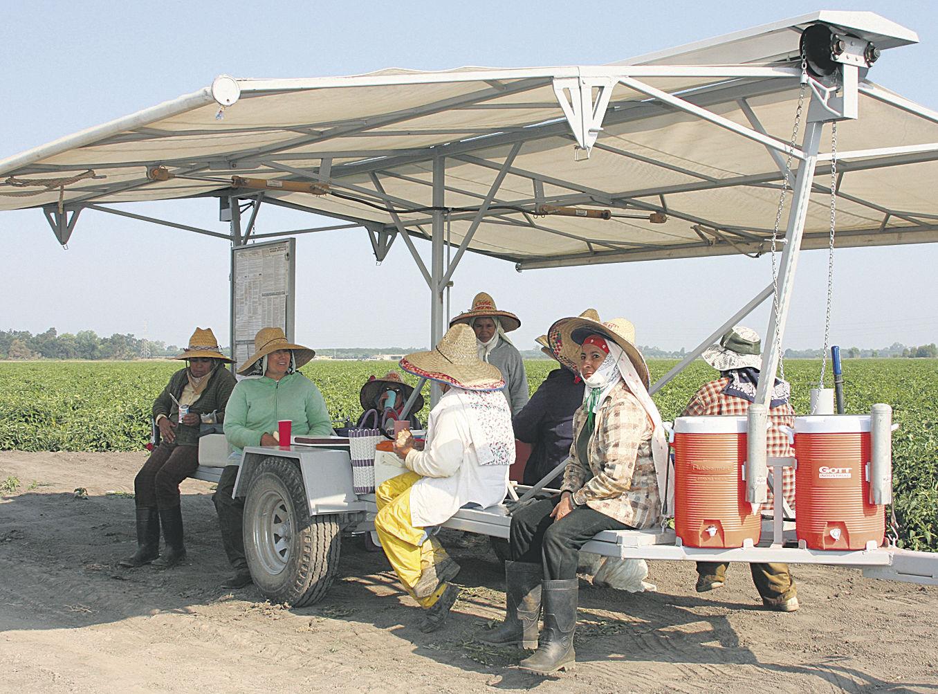 Farmworkers seated in a mobile shade station taking a break.